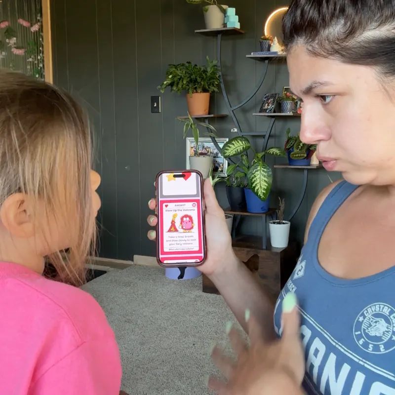 A mom and daughter reading a digital Big Feelings card on a phone together