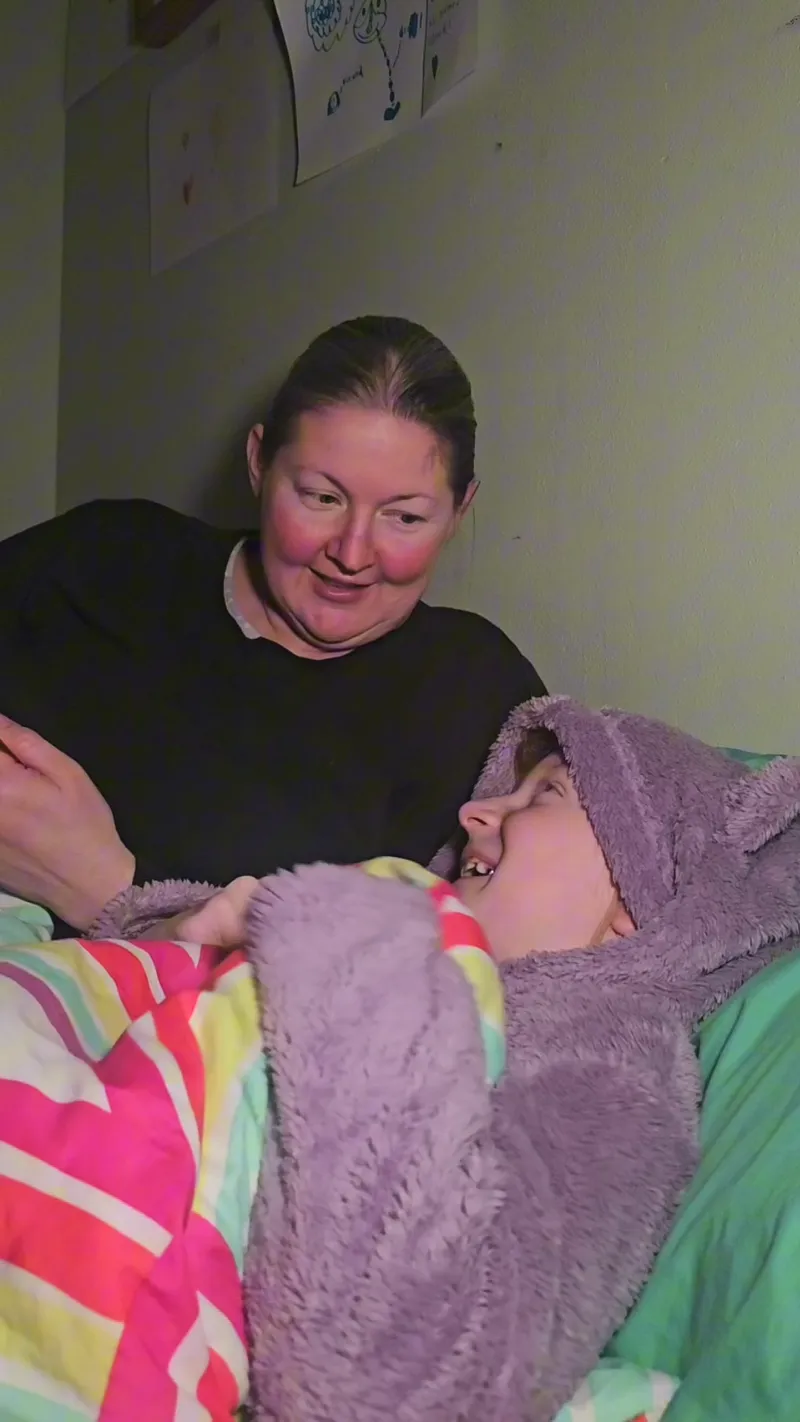 A mom and her giggling child mid bedtime talk
