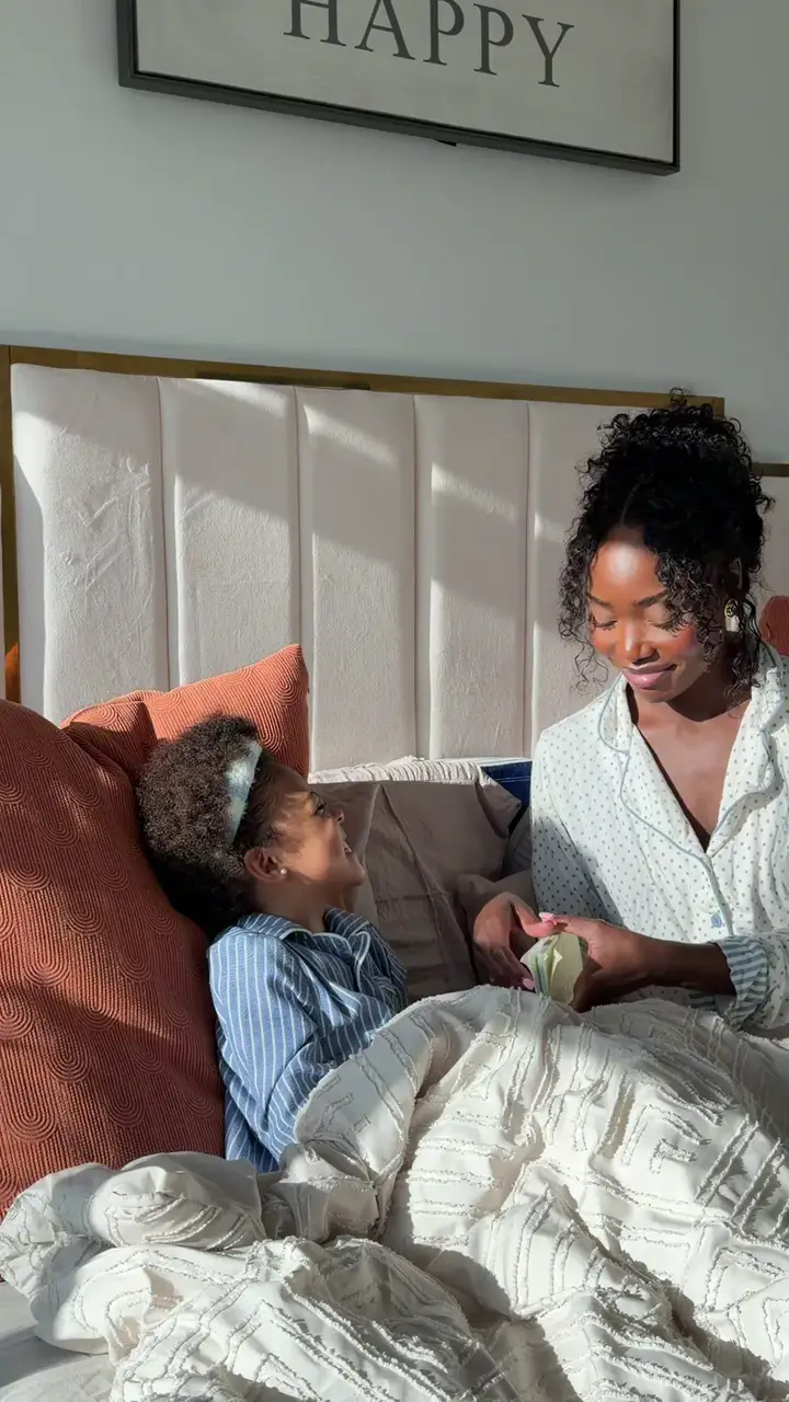 A mom and son going through a card in bed in the morning light