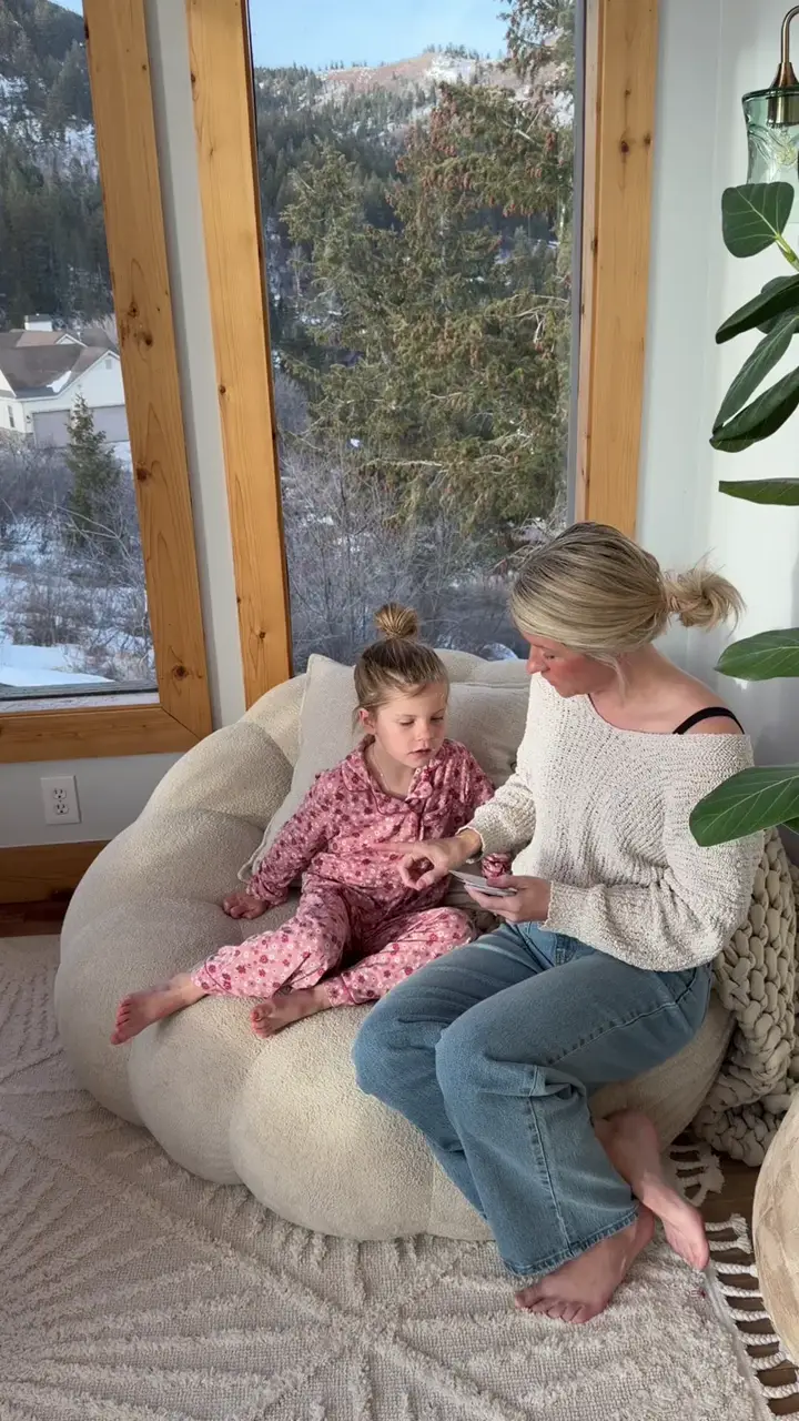 A mom and daughter reading a Body Safety card together on a beanbag