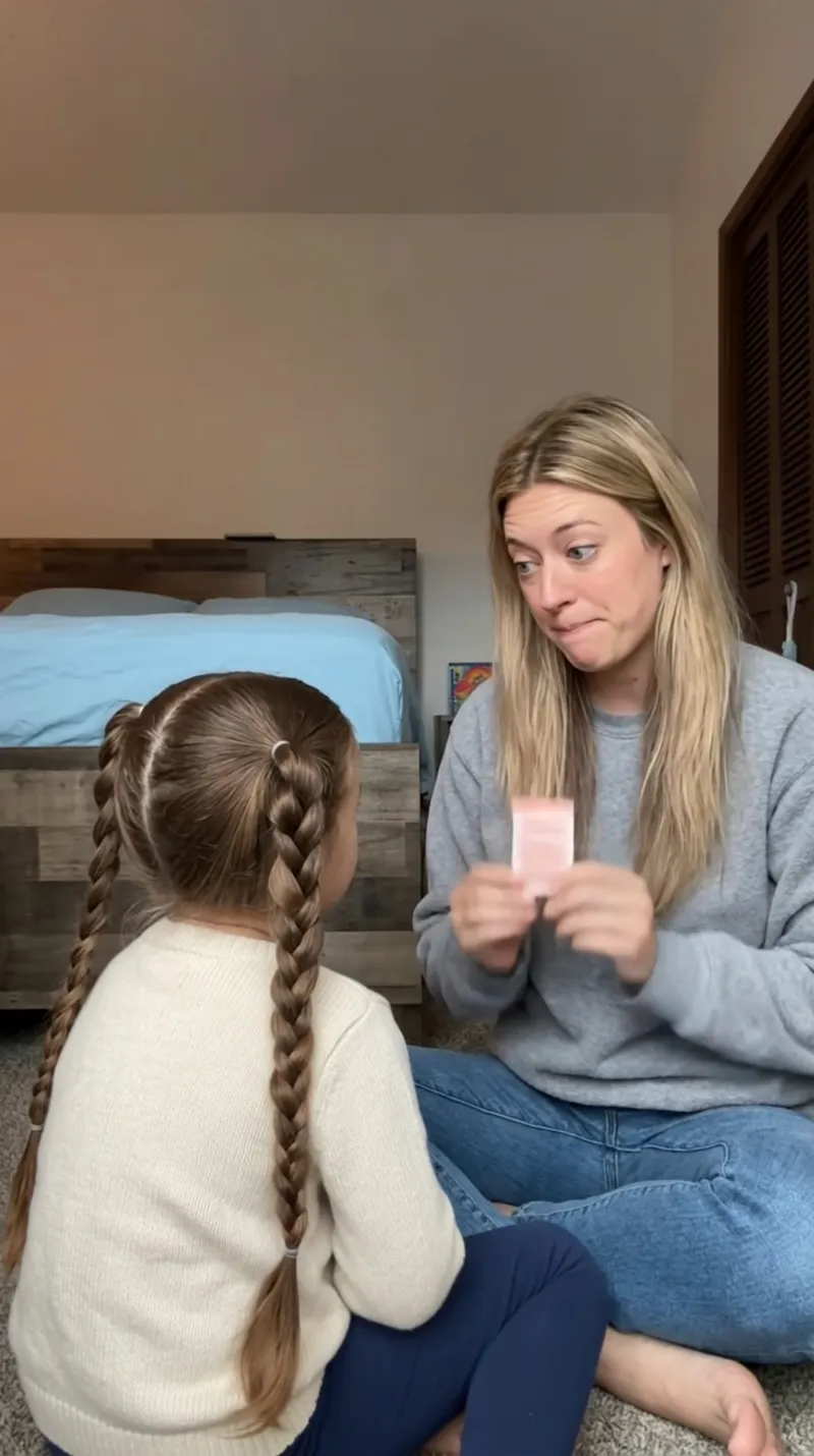 A mom reading a card to her daughter, whose back is to the camera