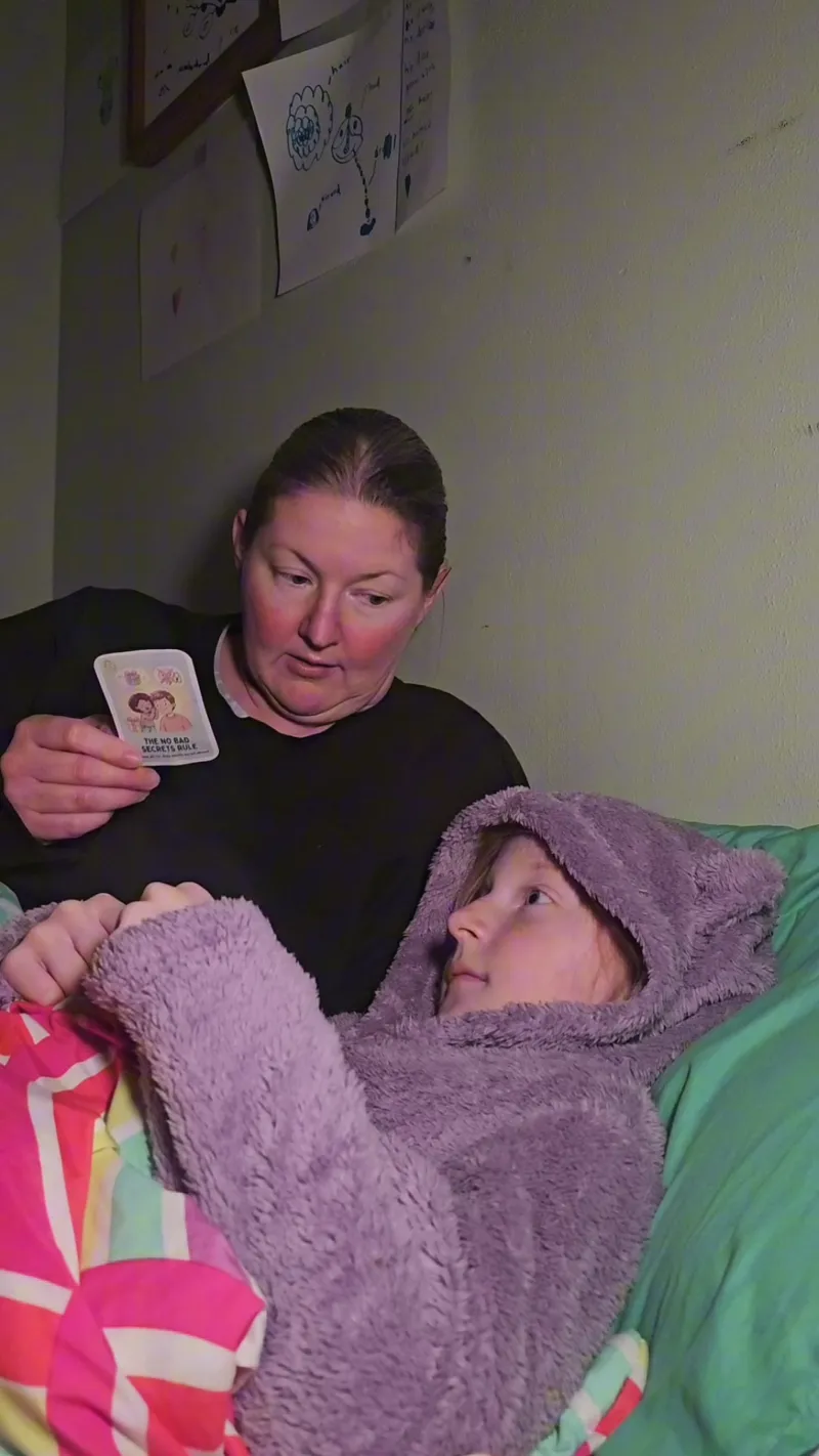A mom holding up the No Bad Secrets Rule card