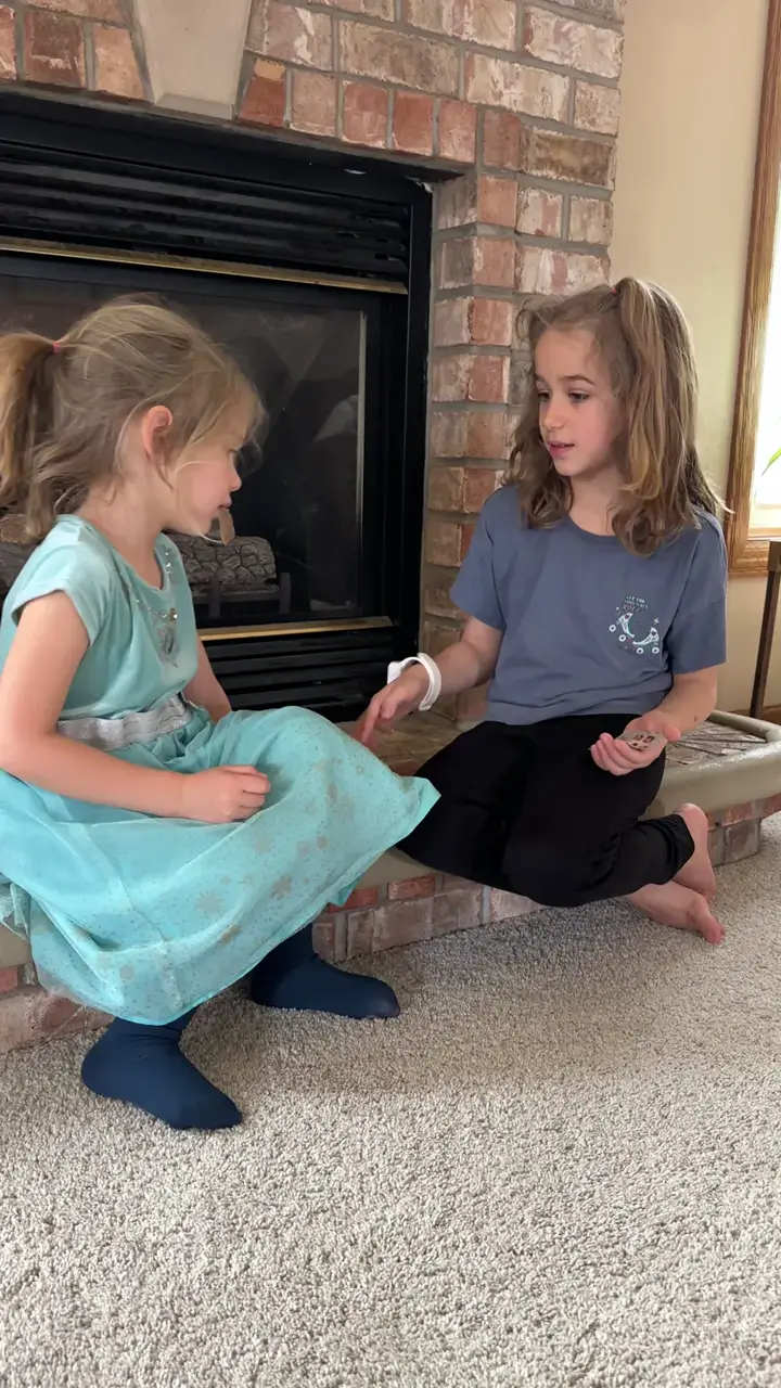 Two sisters practicing the cards together by the fireplace