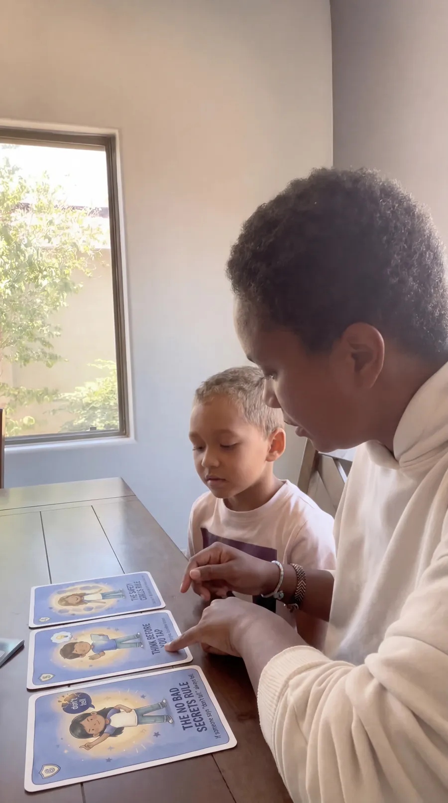 A dad and two kids working through the online safety card spreads on the floor