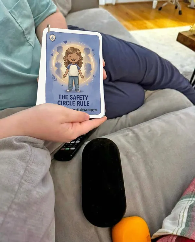 A child on the couch holding a Safety Circle Rule card