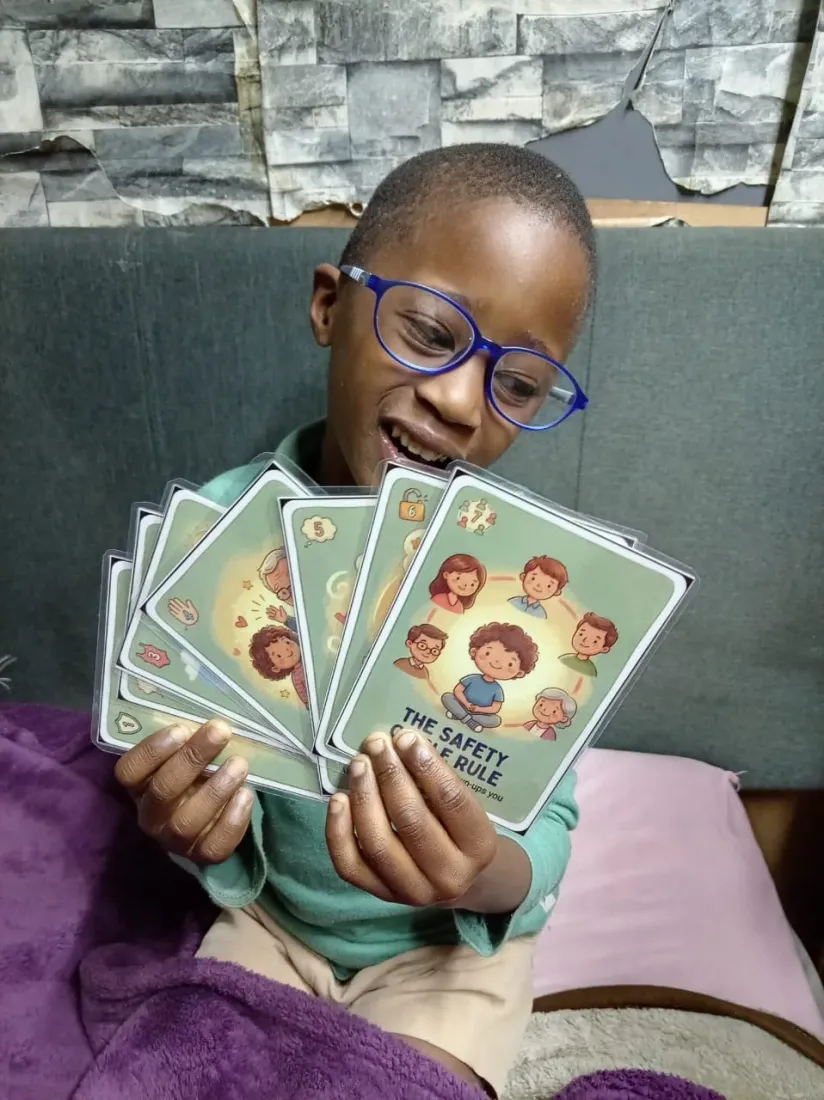 A boy smiling while holding a fan of gifted Trailies safety cards