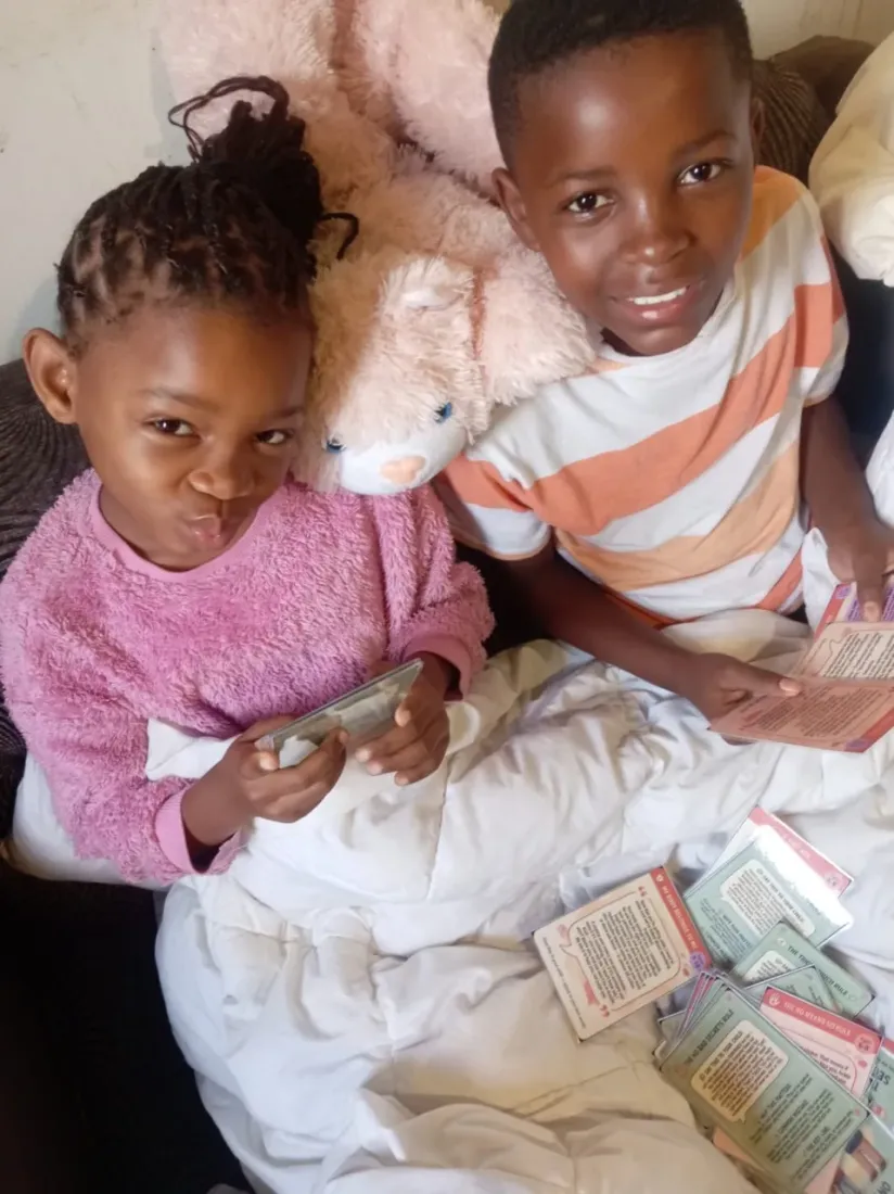 Two young children at Lolla's Light smiling beside a spread of Trailies cards