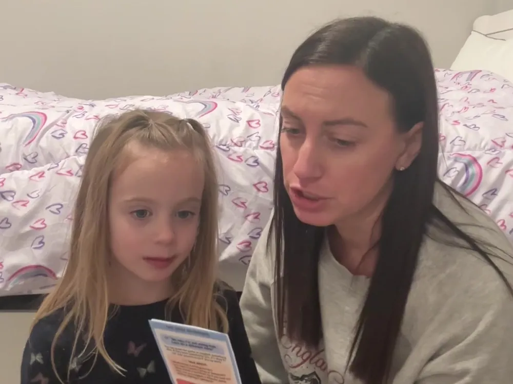 A mom and her daughter reading a Trailies card together